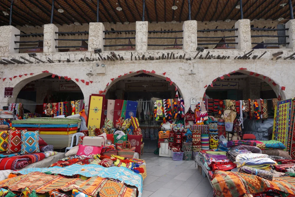 Colourful woven textiles and cushions on display in the stalls of Souq Waqif, Doha