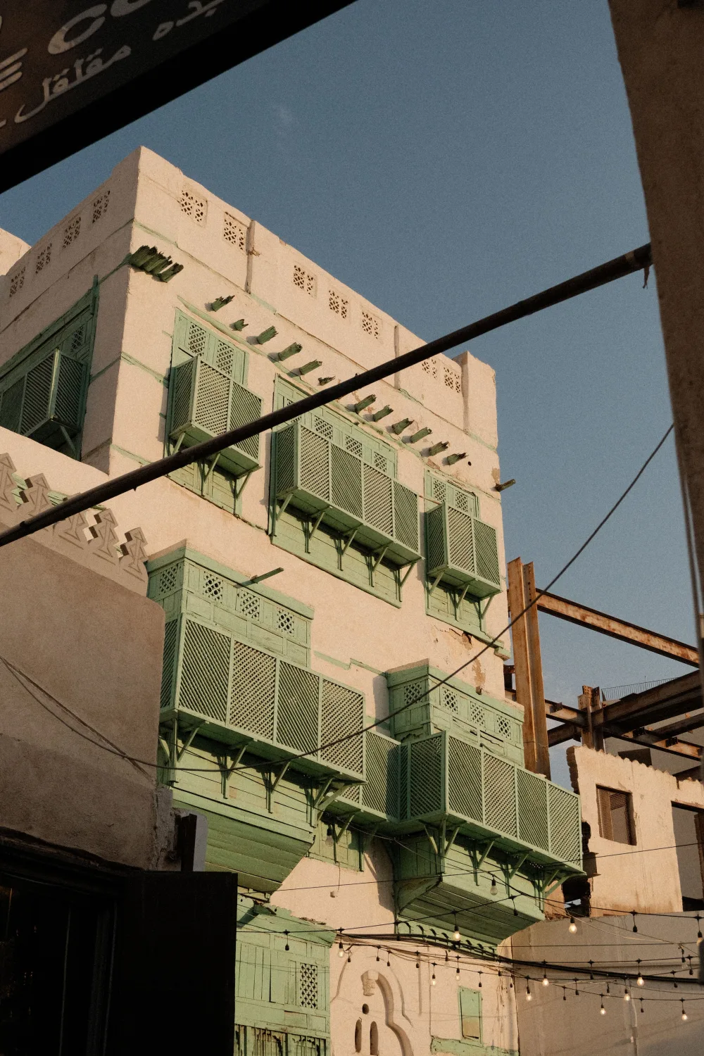 Traditional Hejazi coral-stone architecture with green wooden balconies in the historic Al-Balad district of Jeddah, Saudi Arabia